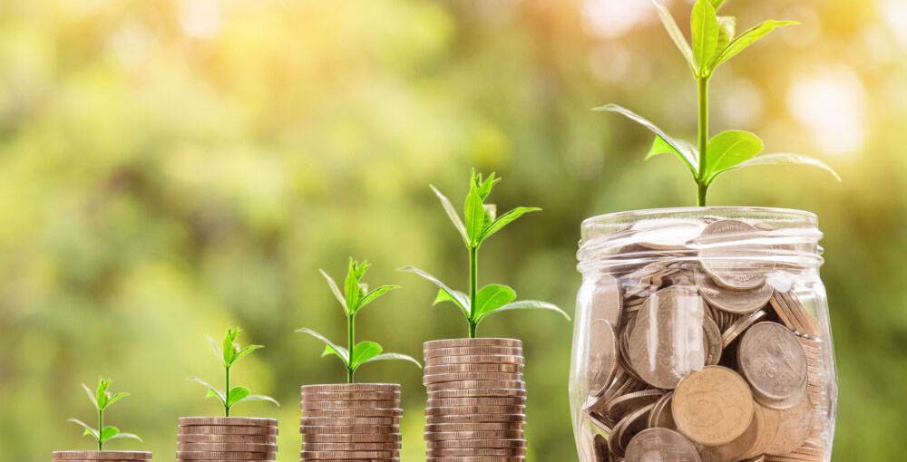 Coins stacked with growing plants and a jar of savings, representing debt recovery, financial growth and successful dispute resolution.