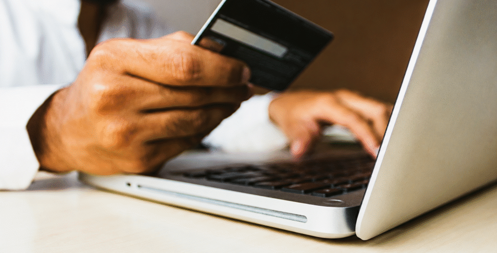 Person making an online payment with a credit card on a laptop, representing debt recovery, payment disputes and financial transactions.