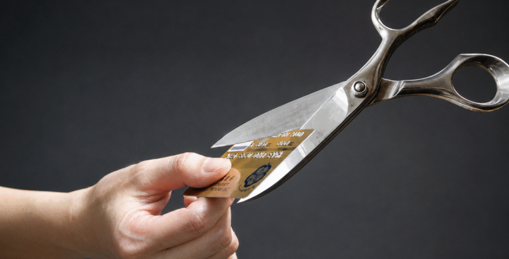 Hand cutting a credit card with scissors, symbolising debt relief, financial recovery and taking control of personal finances.