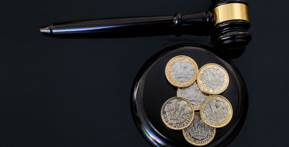 Judge's gavel beside British pound coins, representing legal proceedings, financial disputes and court decisions.