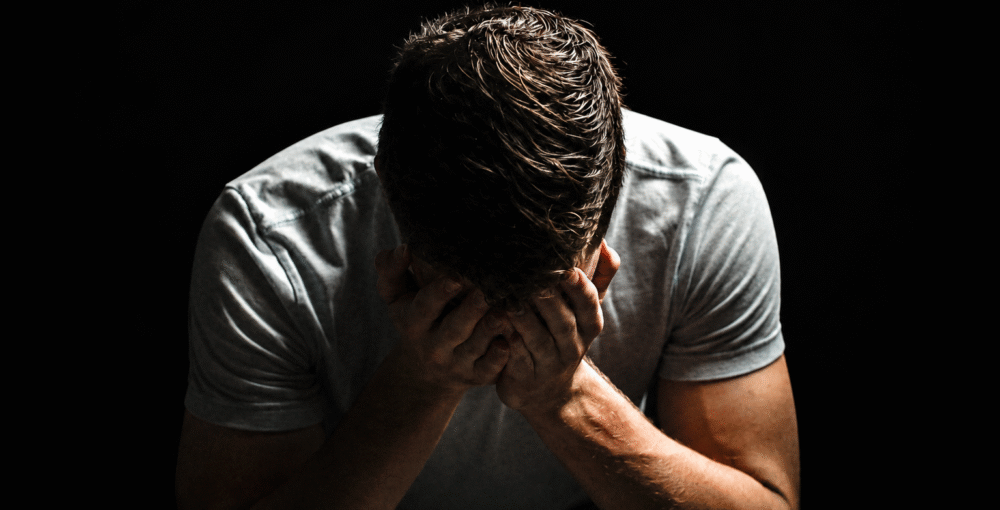 Man sitting with his head in his hands, representing financial stress, debt problems and the need for legal advice.