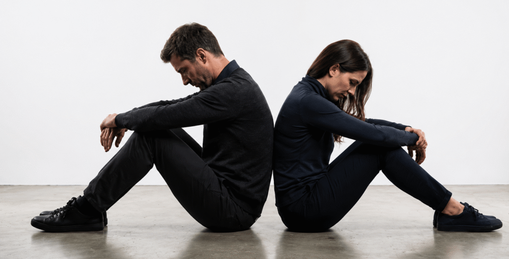 Couple sitting back-to-back on the floor, symbolising separation, relationship breakdown and divorce.